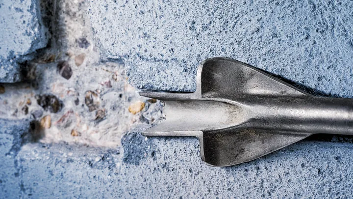Foret à burin perçant un mur en béton.