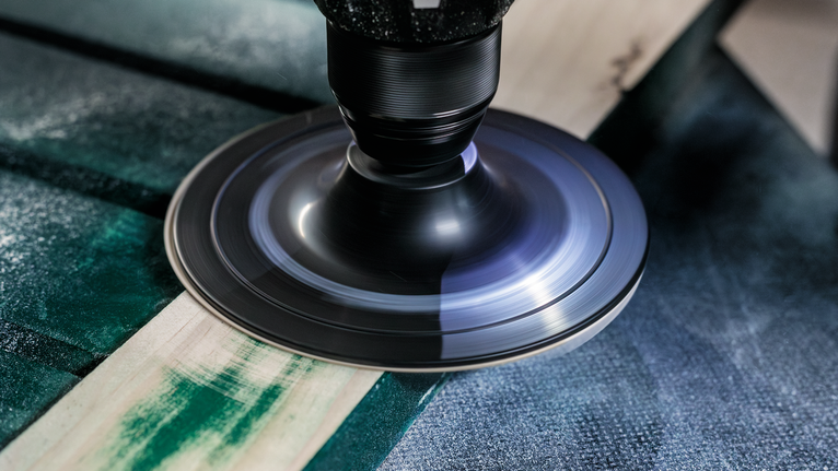 Ponceuse rotative lissant la surface d'une planche de bois.