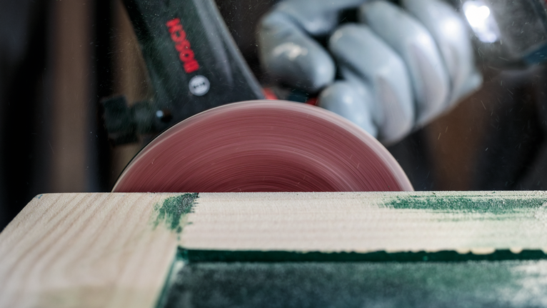 Une personne portant un équipement de sécurité utilise une scie circulaire pour couper du bois.