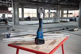 Outil de presse sans fil sur un établi entouré de tuyaux métalliques sur un chantier de construction.