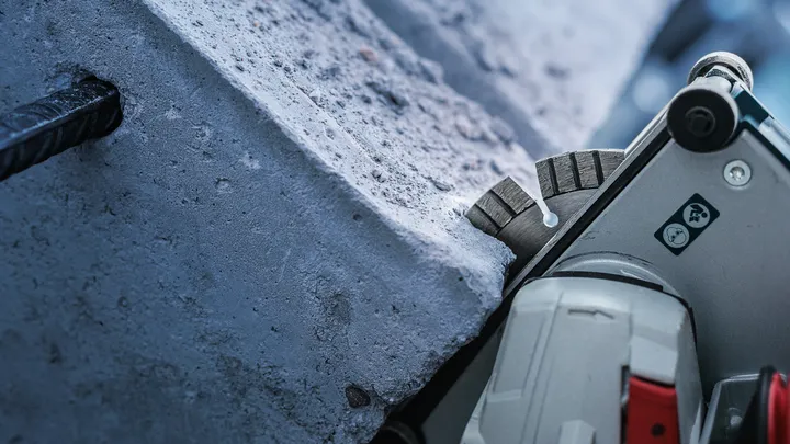 Scie circulaire coupant du béton avec des barres d'armature exposées.
