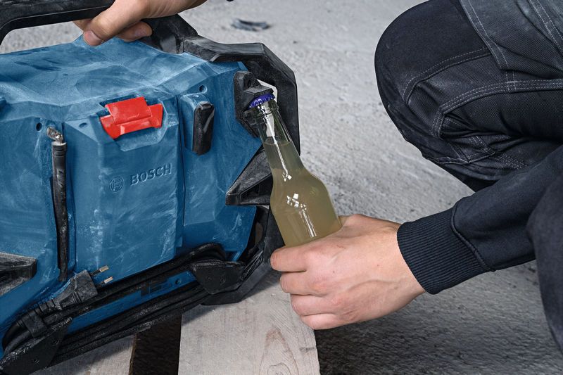 Une personne utilise une radio de chantier portable pour ouvrir une bouteille en verre sur un chantier de construction.
