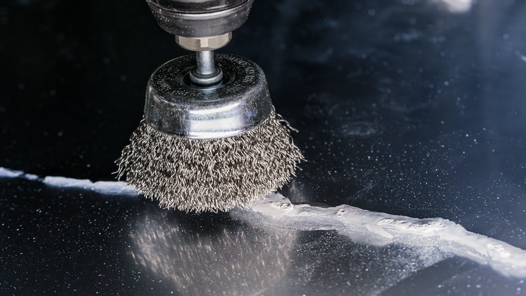 Accessoire de brosse métallique pour nettoyer les résidus d'une surface en marbre fissurée.