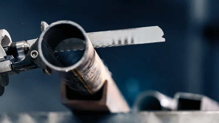 Lame de scie à métaux coupant un tuyau en acier.