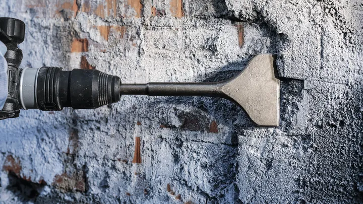 Outil de ciseau brisant la surface d'un mur de briques.