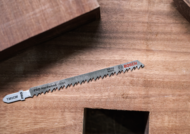 La lame de scie sauteuse pour une coupe nette du bois dur repose sur une surface en bois.