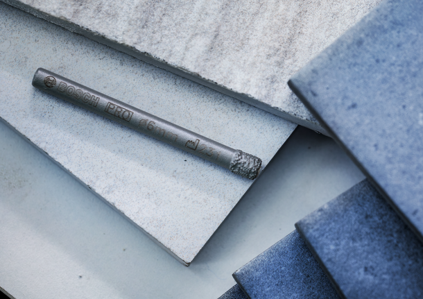 Un foret pour carrelage repose sur des carreaux de céramique et de bleu empilés.