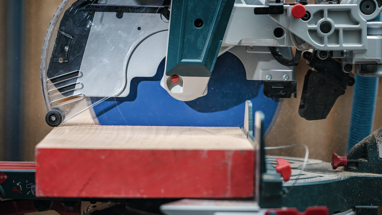 Scie circulaire coupant une planche de bois épaisse dans un atelier.