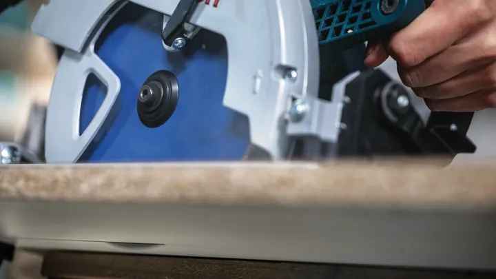 Une personne utilise une scie circulaire pour couper du bois.