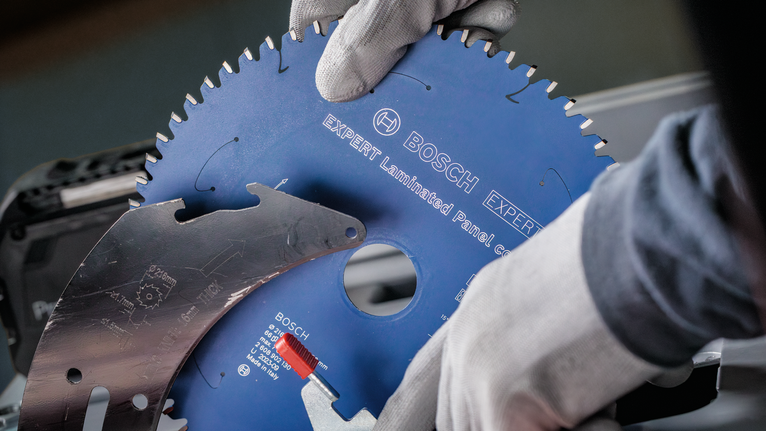 Une personne portant un équipement de sécurité installe une lame de scie circulaire sur une machine.