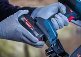 Une personne portant un équipement de sécurité insère une batterie dans une agrafeuse sans fil.