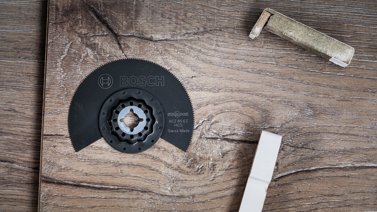 Lame de scie circulaire posée sur une surface en bois, avec des matériaux d'emballage à proximité.