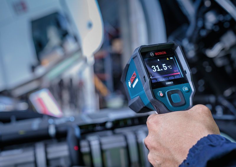 Une personne utilise un détecteur thermique pour mesurer la température des machines.