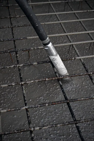 Vibrateur à béton consolidant du béton fraîchement coulé sur une grille d'armature en acier.