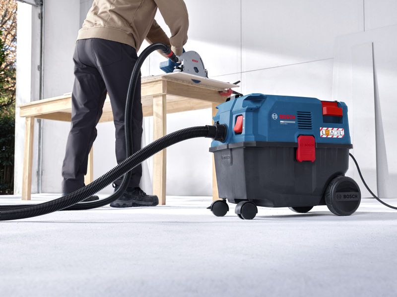 Une personne utilise un extracteur polyvalent relié à une scie pour couper du bois.