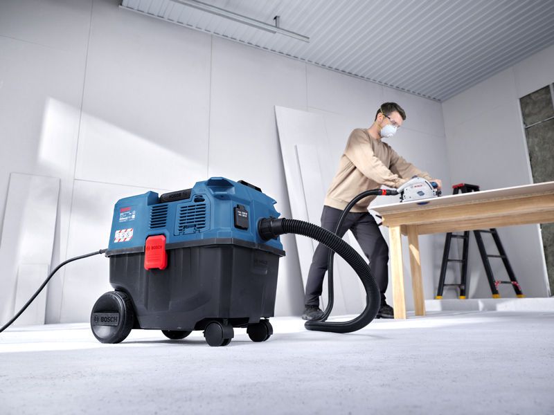 Une personne portant un équipement de sécurité coupe du bois sur une table tout en utilisant une centrifugeuse multifonction.