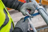 Une personne portant un équipement de sécurité fixe une longe d'escalade à un échafaudage.