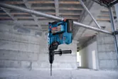 Marteau perforateur sans fil avec SDS plus, suspendu à un tuyau métallique sur un chantier de construction.
