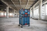 Un chariot de chantier à roulettes, rempli de caisses, se trouve dans un grand bâtiment en construction.