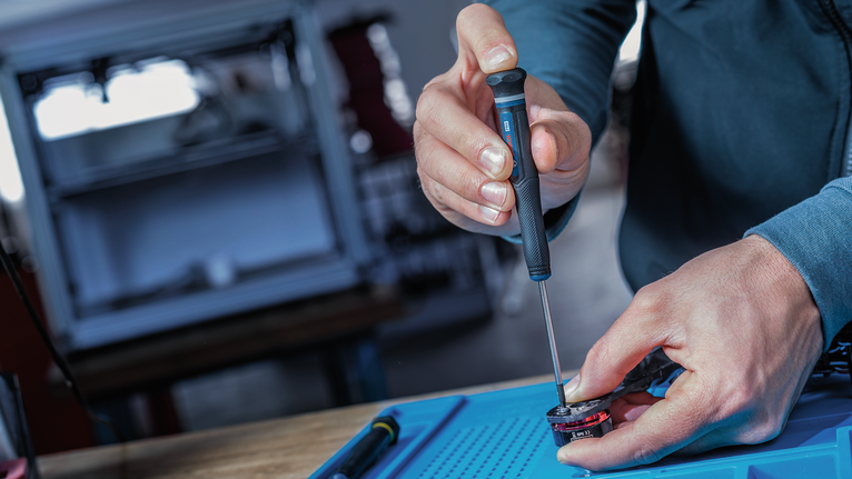 Une personne utilise un tournevis pour assembler un petit composant électronique.
