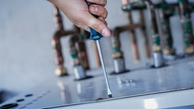 Personne utilisant un tournevis pour fixer une vis sur une surface métallique.