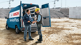 Deux hommes discutent près d'un camion Bosch ServicePlus sur un chantier de construction.