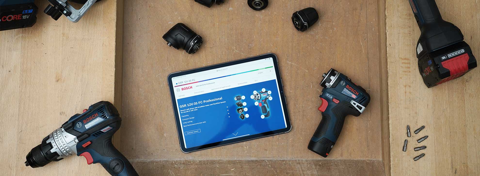 Outils Bosch Professional disposés sur un plan de travail en bois, avec une tablette affichant des informations.