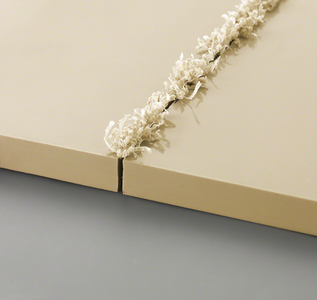 Twee beige panelen met een verse groefsnede en gekrulde spaanders langs de rand.