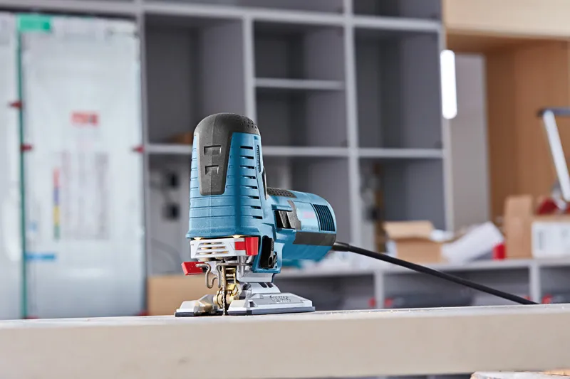 Blauwe decoupeerzaag op een tafelblad in een werkplaats.