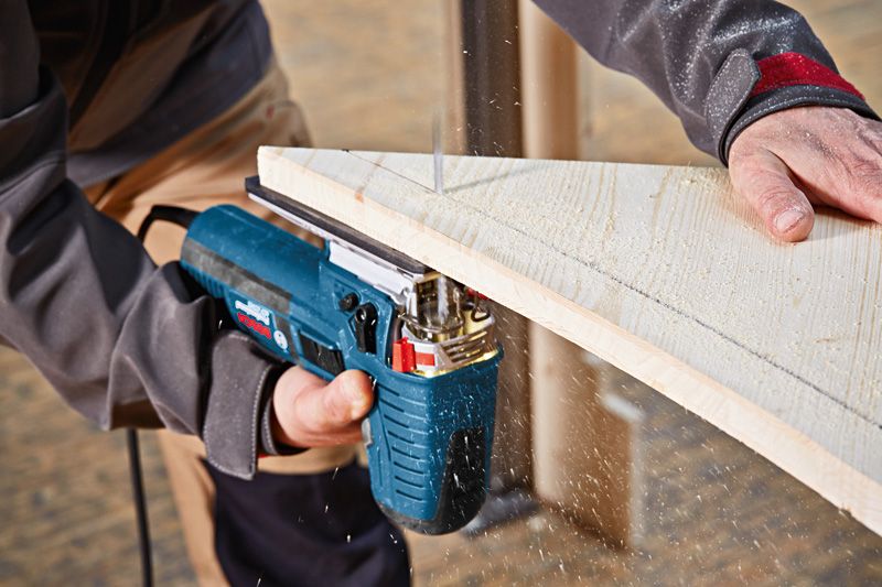 Met een decoupeerzaag zaagt iemand een houten plank.