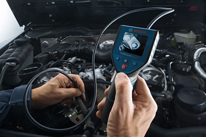 Iemand inspecteert een motor met een inspectiecamera en bekijkt de resultaten op het scherm van het apparaat.