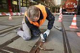 Een persoon die veiligheidsuitrusting draagt, gebruikt een multi-cutter om materiaal uit een betonvoeg te verwijderen.