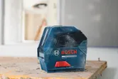 Laserwaterpas op een stoffige werkbank in een bouwomgeving.