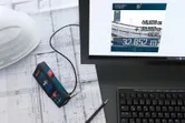 Lasermeter aangesloten op een computer die metingen weergeeft op technische blauwdrukken.