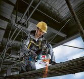 Een persoon die veiligheidsuitrusting draagt, gebruikt een haakse slijper om metalen balken te zagen.