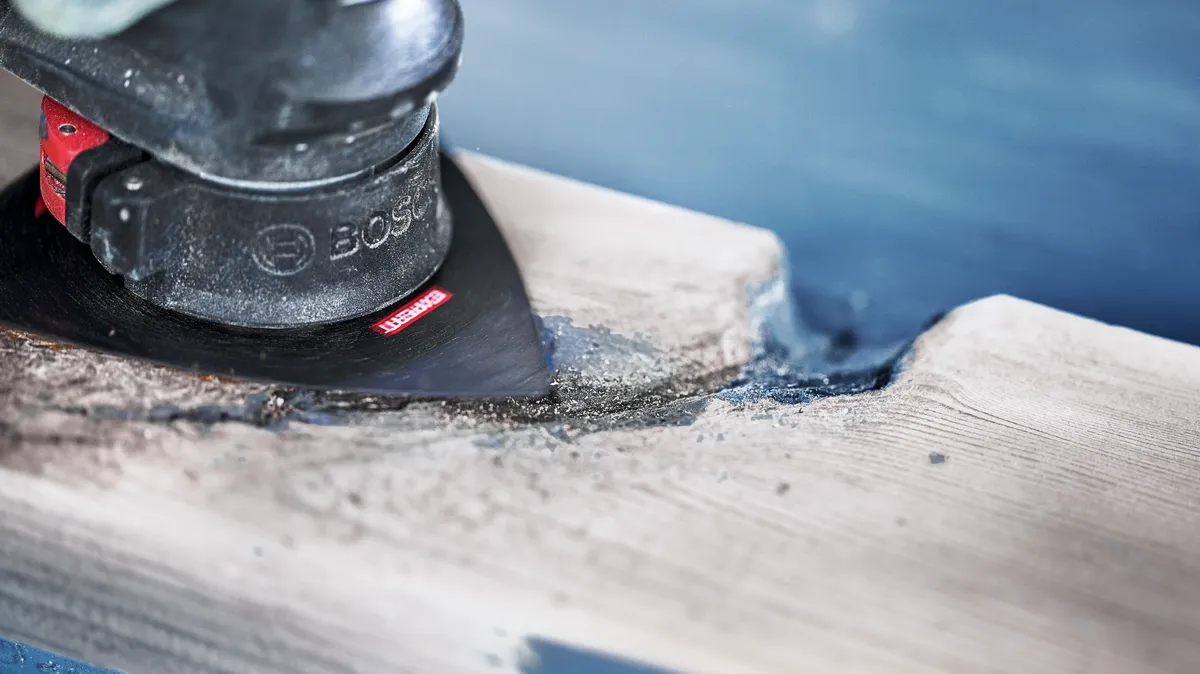 Oscillerende multitool voor het schuren en vormen van een stuk hout.
