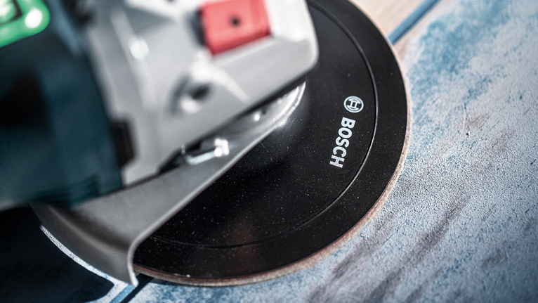 Haakse slijper die door een tegeloppervlak slijpt.