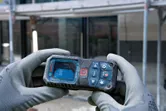 Een persoon die veiligheidsuitrusting draagt, gebruikt een laserafstandsmeter op een bouwplaats.