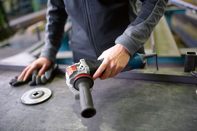 Een persoon bereidt zich voor om een haakse slijper te gebruiken op een metaalwerkbank.