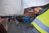 Een persoon die veiligheidsuitrusting draagt, gebruikt een reciprozaag om een metalen pijp door te zagen.