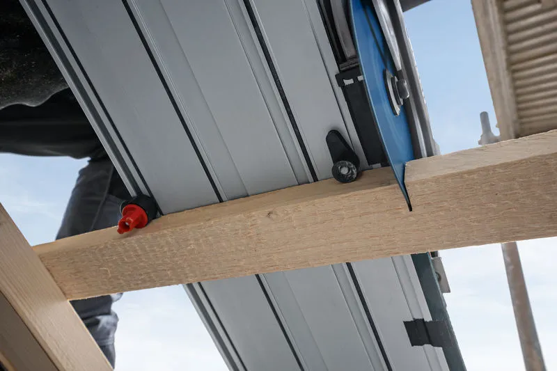 Met een invalzaag wordt een houten balk op een bouwplaats doorgezaagd.