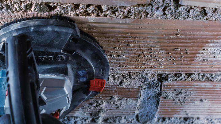 Elektrisch gereedschap voor het slijpen van horizontale groeven in een bakstenen muur.