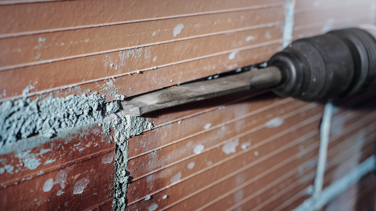 Beitelgereedschap voor het verwijderen van mortel van een betegelde muur.