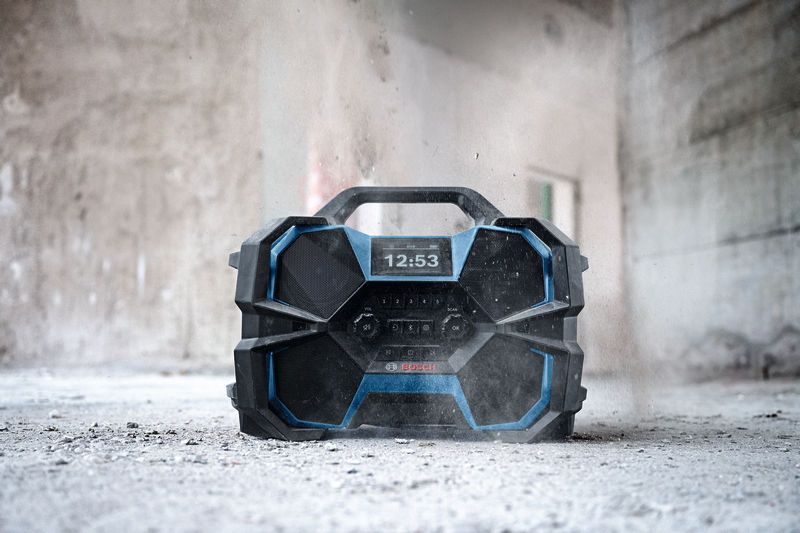 Robuuste bouwradio op een stoffige betonnen vloer in een half afgewerkt gebouw.