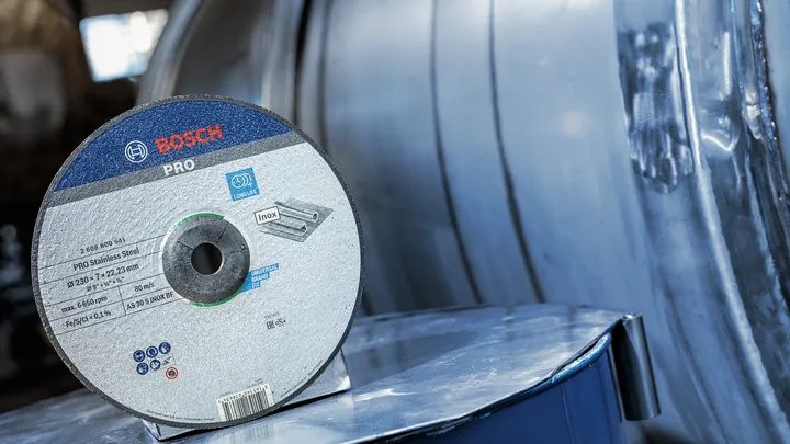 Doorslijpschijf voor roestvast staal, rustend op een reflecterend metalen oppervlak.