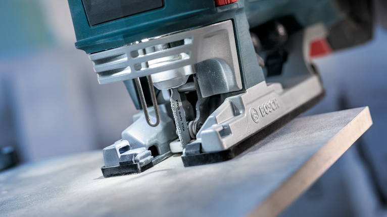 Zaag met een decoupeerzaag door een houten plank in een close-up werkplaatsomgeving.