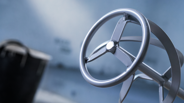 Metalen mengstaaf voor elektrisch gereedschap, onscherpe industriële achtergrond.