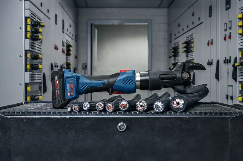 Snoerloos hydraulisch snijgereedschap op een werkbank naast dikke elektrische kabels.