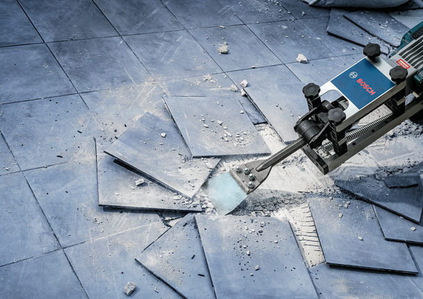 Elektrisch gereedschap met beitelhulpstuk voor het verwijderen van kapotte vloertegels en het creëren van puin.