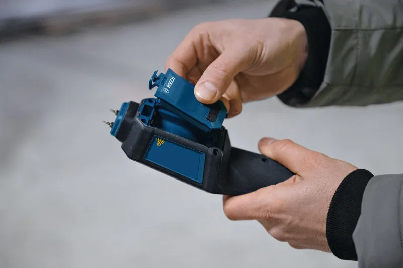 Iemand plaatst een batterij in een vochtmeter voor materialen.